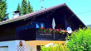 ein schwarzes Haus mit Blumen im Fenster in der Unterkunft Ferienwohnung Neuhuber in Bad Goisern