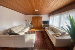 a living room with white couches and a wooden ceiling at Familien-Haus,Garten,Grill,20m zum Rhein in Stein am Rhein