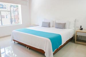 a white bedroom with a large bed with blue blanket at Hotel Boutique Laureles Medellin (HBL) in Medellín