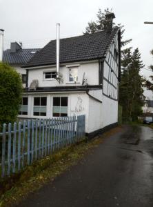 a white and black house with a fence at My Home is my Castle in Hontheim