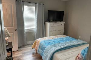 a bedroom with a bed and a dresser with a television at Siesta Key Village-Suite #4: A block to the Beach! in Sarasota