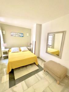 a bedroom with a yellow bed and a mirror at Apartamentos Tapahuga in Playa de Santiago