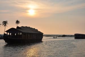 un barco en el agua con palmeras. en Backwater Breeze, en Kumarakom