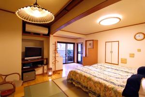 a bedroom with a large bed and a tv at Masutomi Ryokan in Hakone