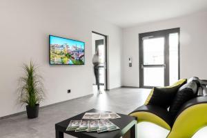 a living room with a couch and a tv on a wall at Hotel Grüne Elster in Fürth