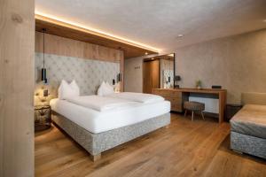 a bedroom with a large white bed and a desk at SonnenHOF hotel gerlos centrum in Gerlos