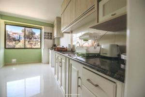 a kitchen with white cabinets and a green wall at Hermoso y acogedor departamento en lugar apacible in Sucre
