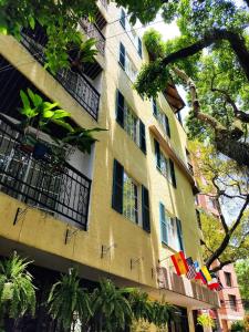 a tall yellow building with windows and trees at Casa del Hidalgo Hotel Cali Centenario in Cali
