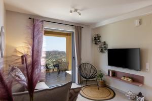 sala de estar con TV y puerta corredera de cristal en Villa Zoe , south Crete , Triopetra, en Triopetra