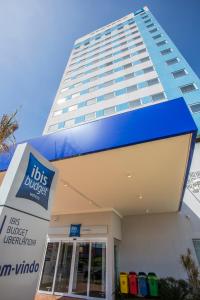 a tall building behind a building with a store at ibis budget Uberlandia in Uberlândia