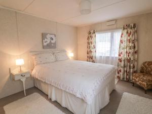 a bedroom with a bed and a window and a chair at The Lodge in Attleborough