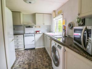 uma cozinha com armários brancos e uma máquina de lavar e secar roupa em The Lodge em Attleborough