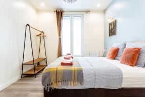 - une chambre avec un grand lit et des oreillers orange dans l'établissement StayLib - GARIBALDI 2 PIECES PORTE DE MONTMARTRE, à Saint-Ouen