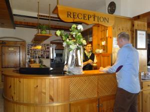 a man standing at a counter with a vase of flowers at Pension Scherwirt in Graz +11 photos