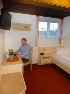a man sitting at a desk in a room at Pension Scherwirt in Graz