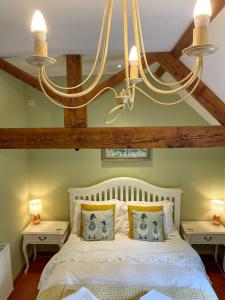 a bedroom with a white bed and a chandelier at Idyllic Suite at Lower Fields Farm in Napton on the Hill