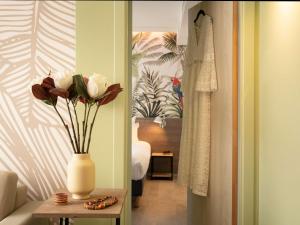 a room with a vase with flowers on a table at ibis Styles Beaulieu sur Mer in Beaulieu-sur-Mer