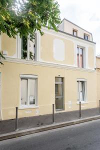 StayLib - Lovely 2 rooms porte de Montmartre في سانت وان: مبنى اصفر على جانب شارع