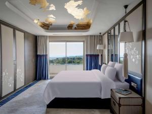 a bedroom with a white bed and a large window at Rixos Premium Belek - The Land of Legends Access in Belek