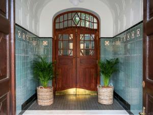 drewniane drzwi z dwoma doniczkami przed nimi w obiekcie Heritage Hotel FERMAI MGallery Split w Splicie