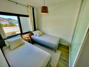um pequeno quarto com 2 camas e uma janela em Ocean Cliff Apartment em Santa Cruz - Madeira