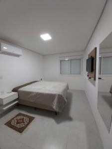 a white bedroom with a bed and a television at Apartamento em Torres in Torres