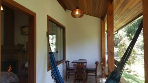 a room with a table and chairs and a hammock at Cabanas da Fazenda in Visconde De Maua