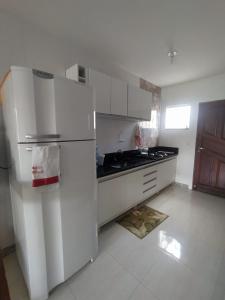 uma cozinha branca com um frigorífico e um lavatório em Casa de Praia Lado Sul em Guriri