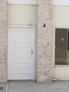 a white garage door next to a brick wall at Sobrado 4 amplo e confortável em condomínio in Corumbá