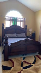 a large wooden bed in a bedroom with a window at Luxurious Secret Escape in Portmore