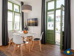 ein Esszimmer mit einem Tisch, Stühlen und einer grünen Tür in der Unterkunft Villa Frohsinn Whg. 12 in Bansin