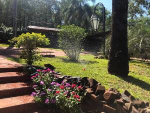 a garden with flowers and a stone wall at Stone Wall Cottages in Puerto Iguazú