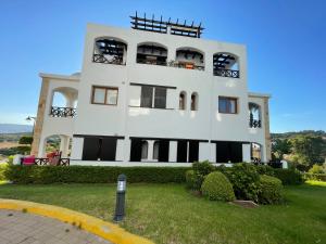 a large white building with windows and a yard at Lilac Gardens Resort in Cabo Negro