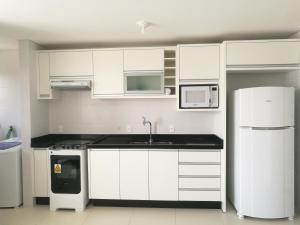 una cucina con mobili bianchi e un frigorifero bianco di EA-Apto com vista do mar em Praia dos Ingleses a Florianópolis