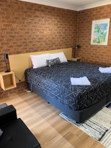 a bedroom with a bed and a brick wall at Colonial Motor Inn in West Wyalong