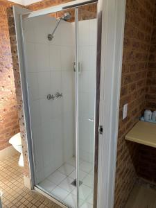 a shower with a glass door in a bathroom at Colonial Motor Inn in West Wyalong