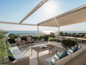 a patio with couches and tables and the ocean at Rixos Premium Belek - The Land of Legends Access in Belek