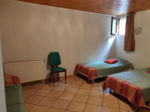 Le Lauzet-UbayeにあるLocation MarjoRI - T3 Le Kakarikiのベッド2台と緑の椅子が備わる客室です。