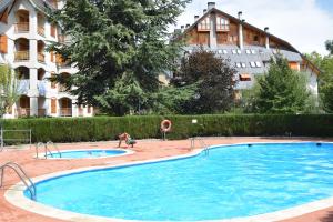 a large swimming pool in front of a building at Acogedor apartamento con piscina compartida y opción a parking in Jaca