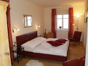 a bedroom with a bed with white sheets and red curtains at Cobaneshof in Gobelsburg