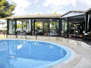 uma piscina ao lado de uma casa com um pavilhão em Lesse Hotel em Hanioti