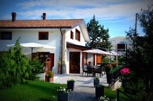 ペスココスタンツォにあるLo Chalet da Ilariaの庭のテーブルと傘を備えた白い家