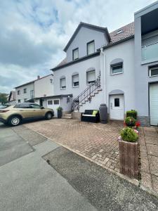 a car parked in front of a white house at Apartment Elegance 2.0 in Höheischweiler