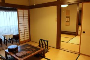 a room with a table and chairs and a window at Historical Ryokan SENYUKAN in Ōwani