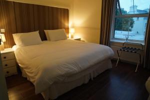Un dormitorio con una gran cama blanca y una ventana en The Fleet Inn, en Killybegs