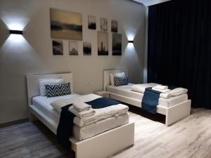 a bedroom with two beds with whiteitures and pictures on the wall at SB River Hotels in Atyrau