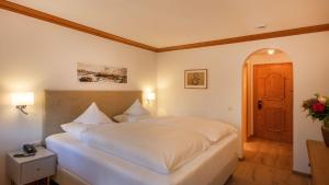a bedroom with a large white bed and a door at Hotel Ziegleder in Rottach-Egern