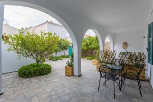 un patio con mesa, sillas y árboles en Aria Apartments en Spetses