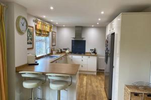 a kitchen with white cabinets and a counter with stools at Stylish and modern home in Uppingham, Rutland in Uppingham