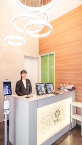 a woman sitting at a counter with two computers at Hotel Xcell 広島 流川通り in Hiroshima